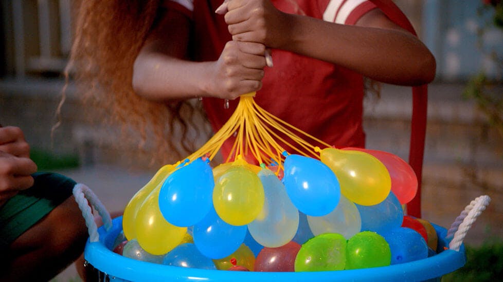 A person filling several water balloons at once.