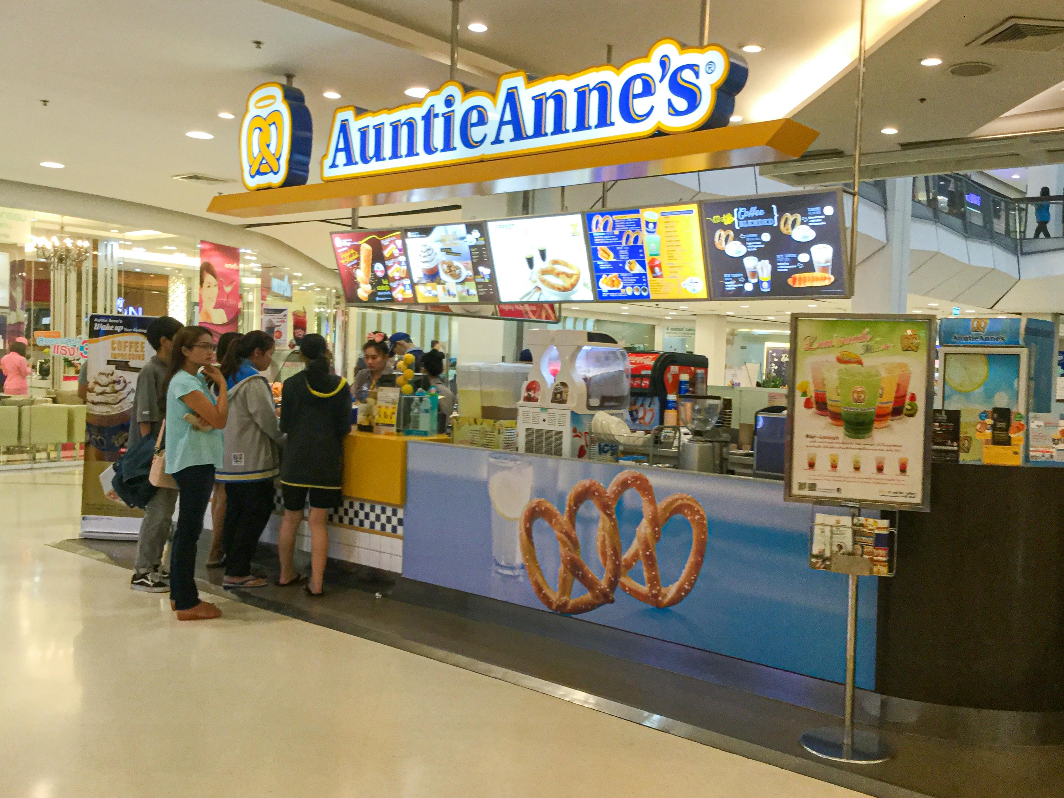 A group of people standing at an Auntie Anne's counter inside a mall.
