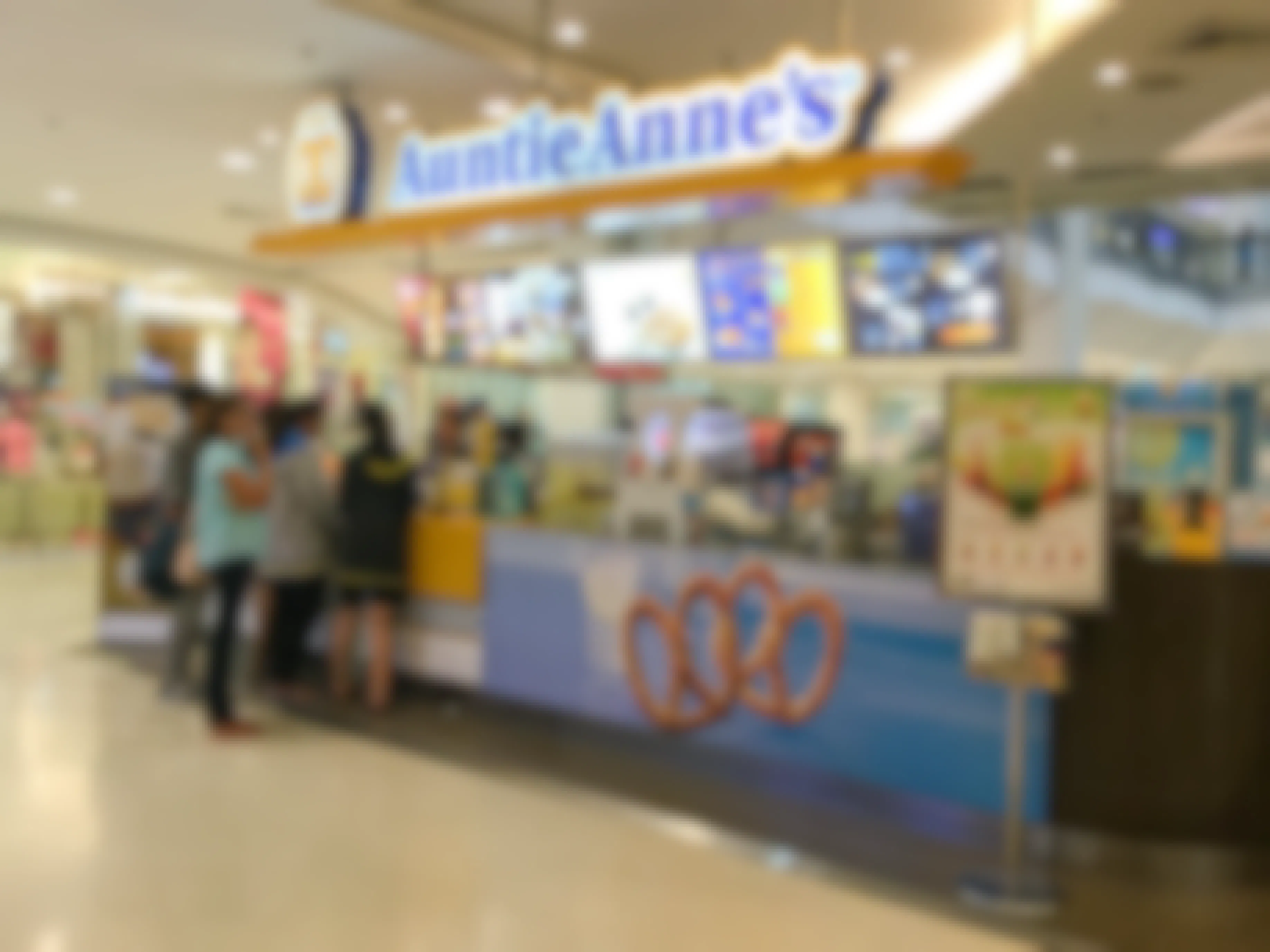 A group of people standing at an Auntie Anne's counter inside a mall.