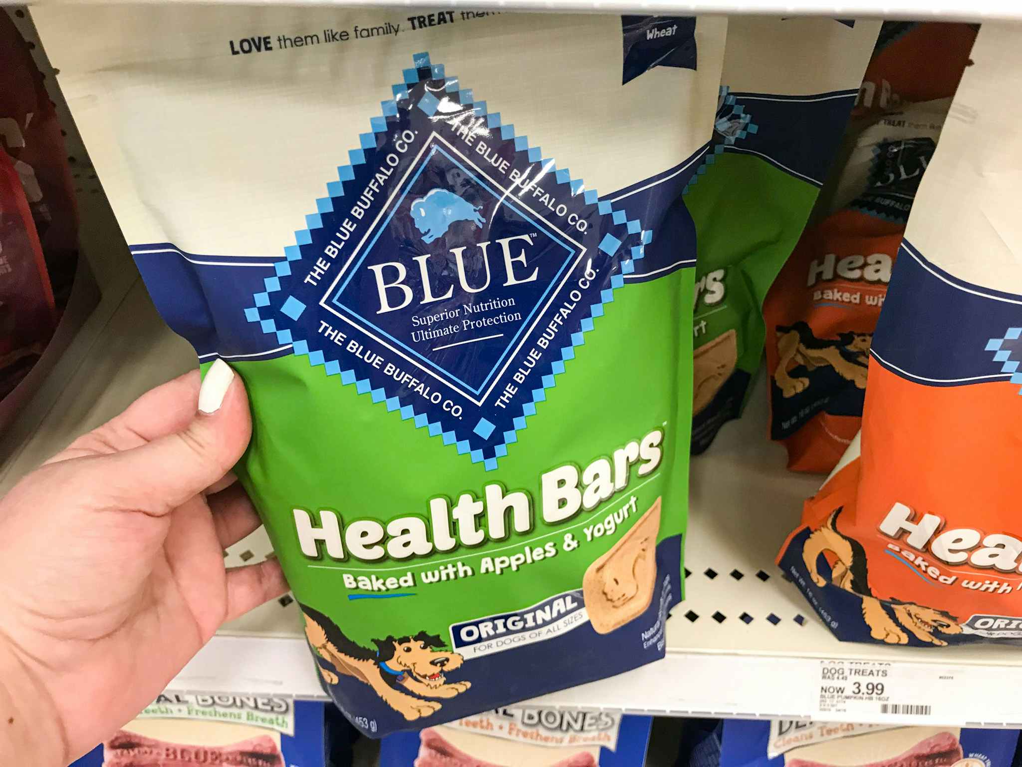 hand grabbing a bag of blue health bars dog treats off a target shelf