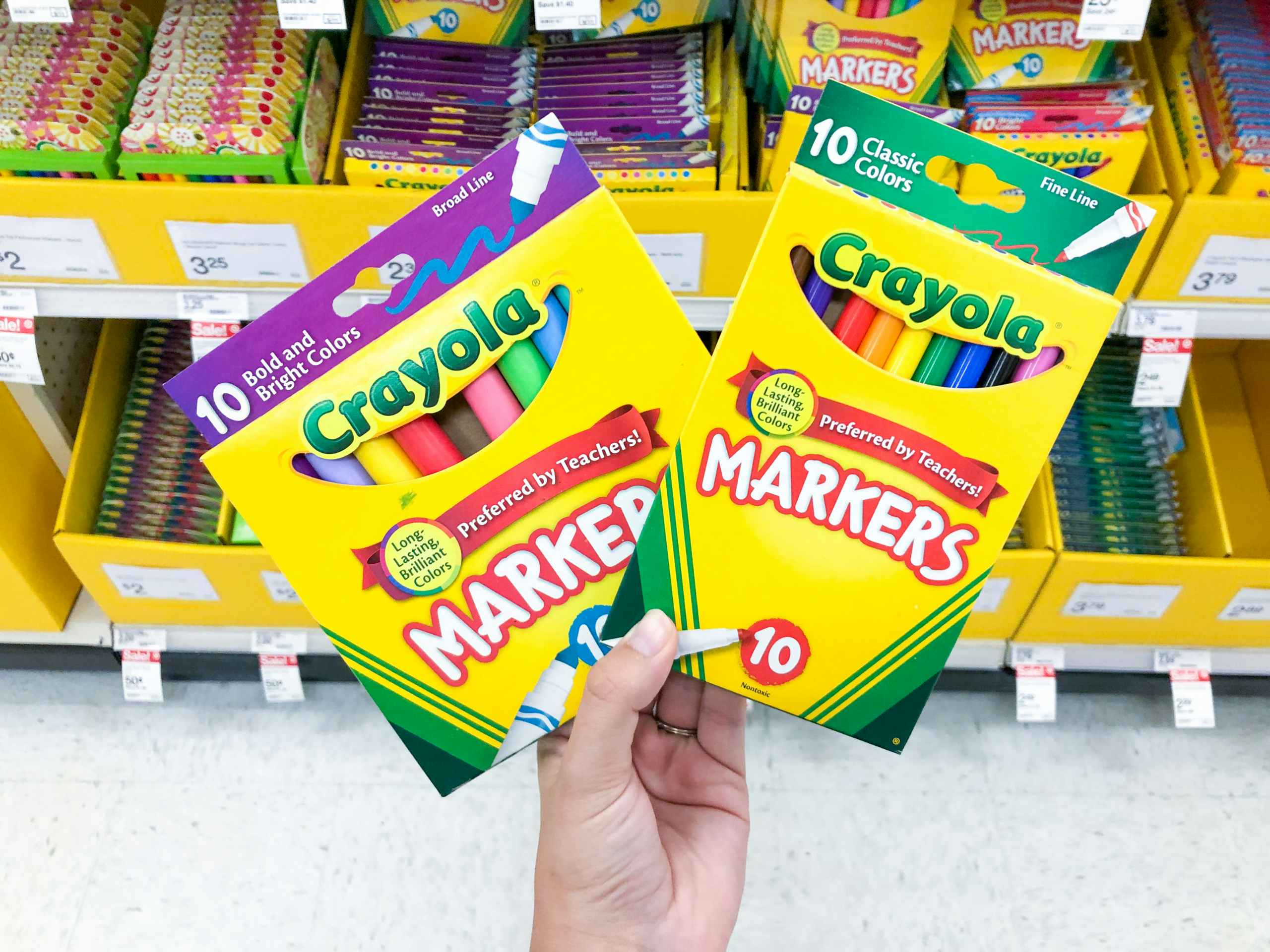 hand holding two pack of Crayola markes in front of back to school section
