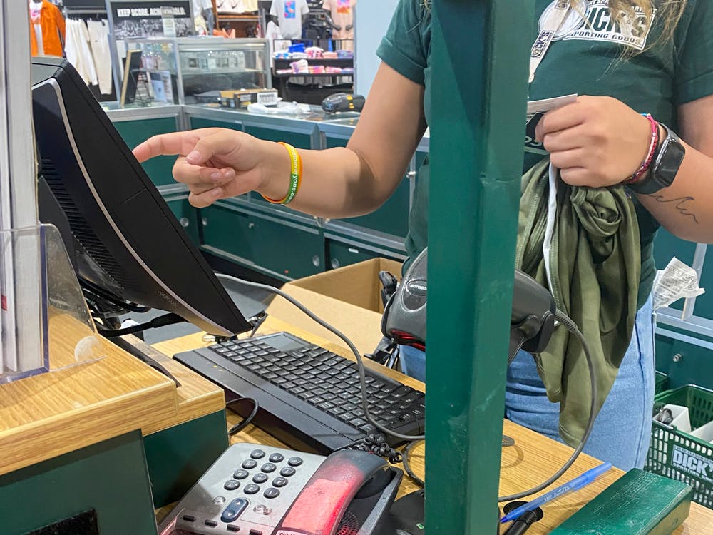 A Dick's Sporting Goods employee at the register ringing up an item.