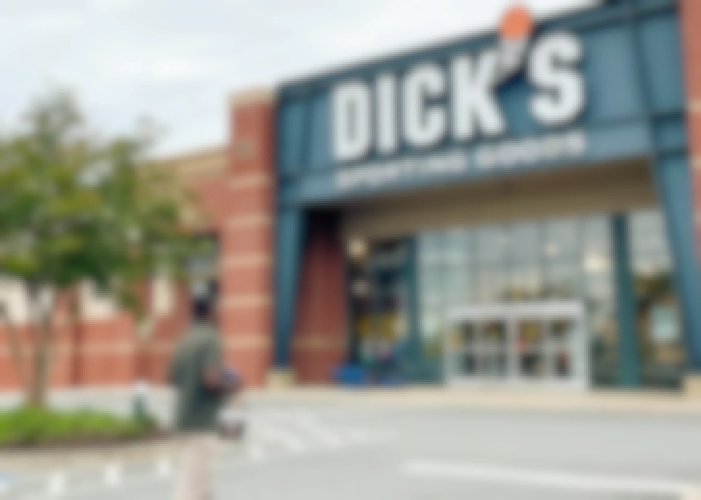 A man walking into Dick's Sporting Goods with items in hand