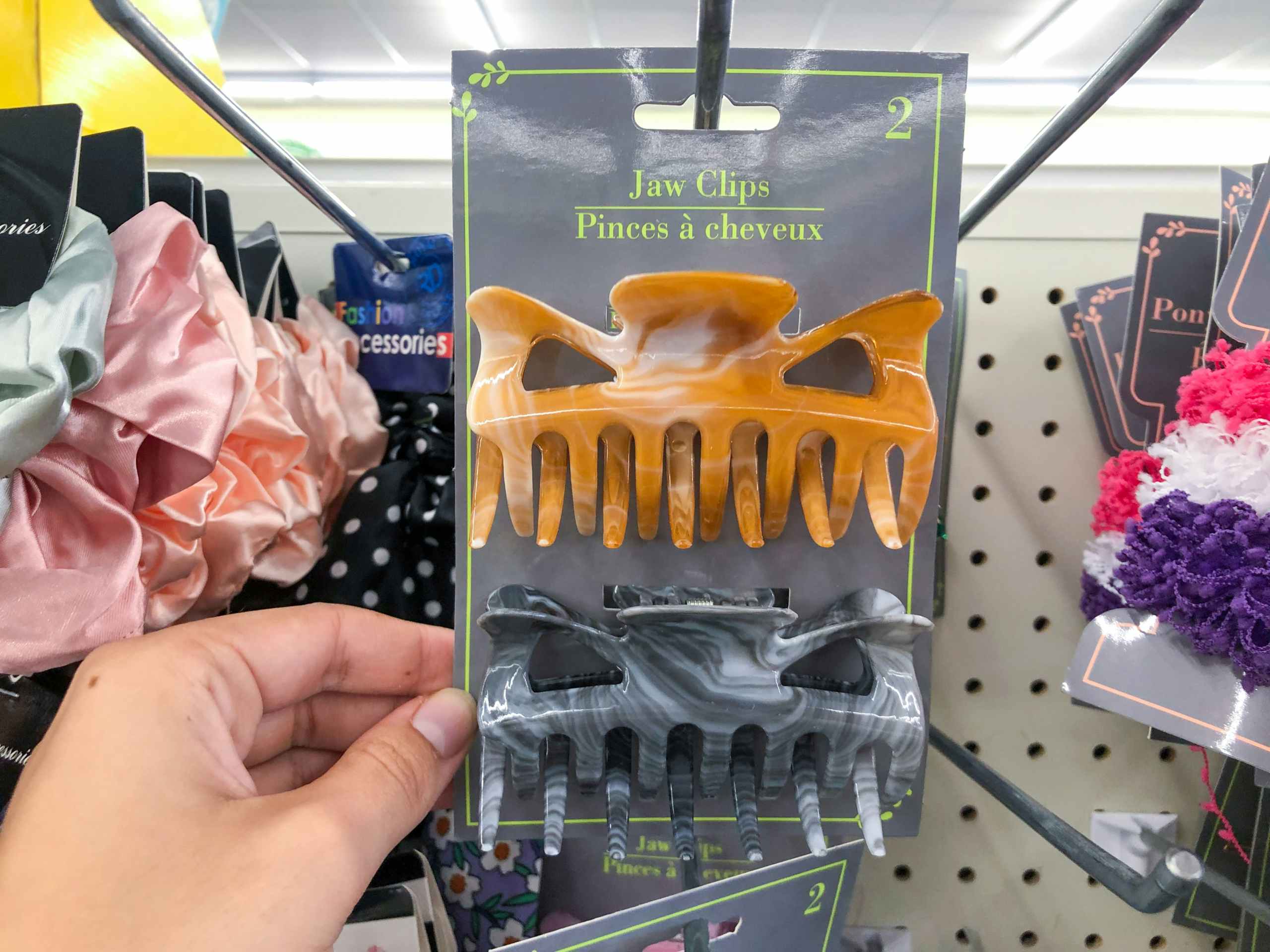 hand holding one two-pack of hair claw clips inside Dollar Tree