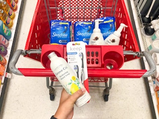 hand holding soap and toothbrush in front of shopping cart