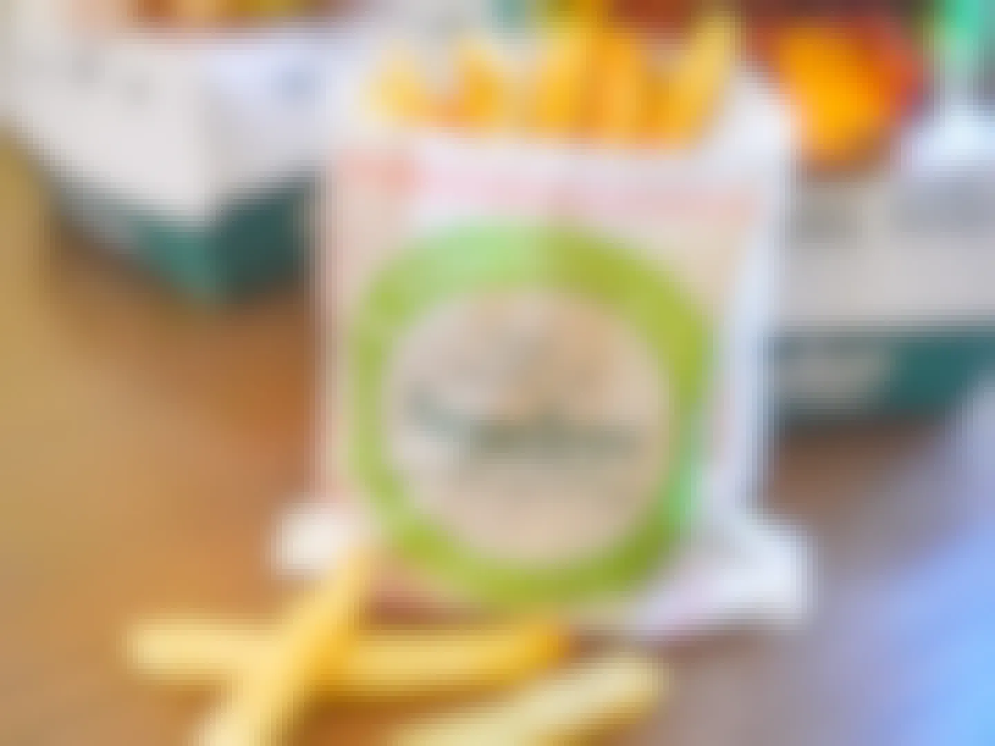 A bag of Farmer Boys french fries and some loose fries on a table in front of some burger boxes.