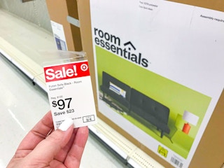 hand holding sale tag in front of boxed futon on store shelf at Target