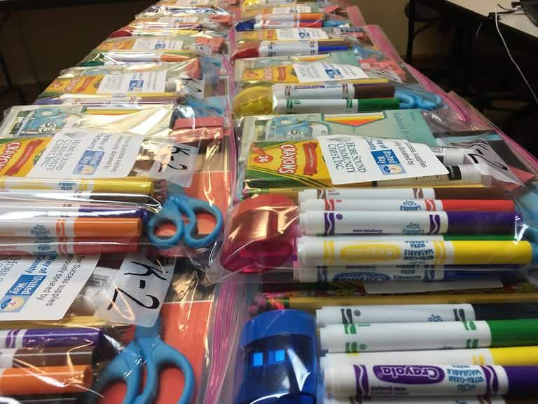 Clear bags of school supplies stacked on a table.