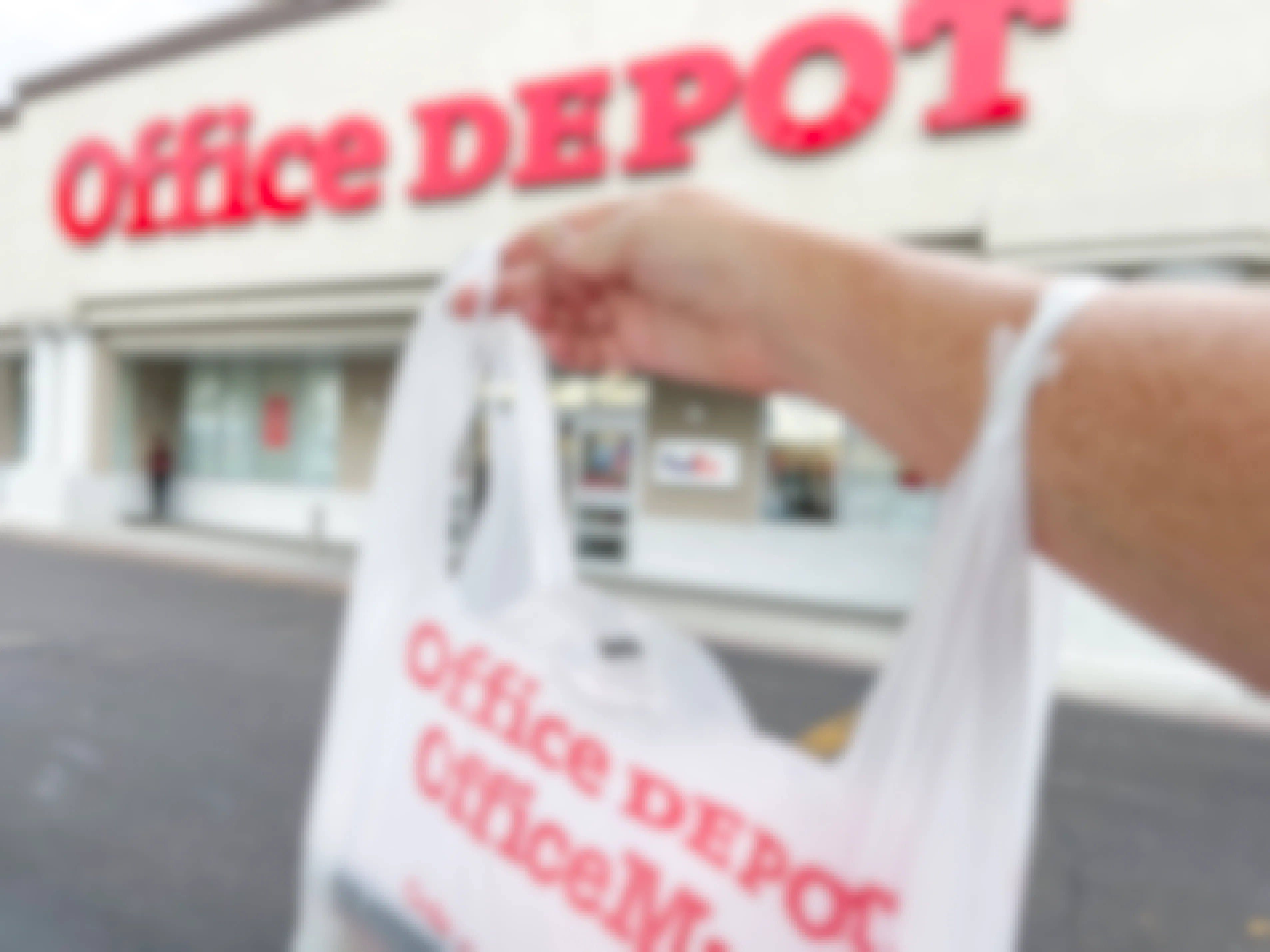 Person holding an Office Depot bag outside an Office Depot store