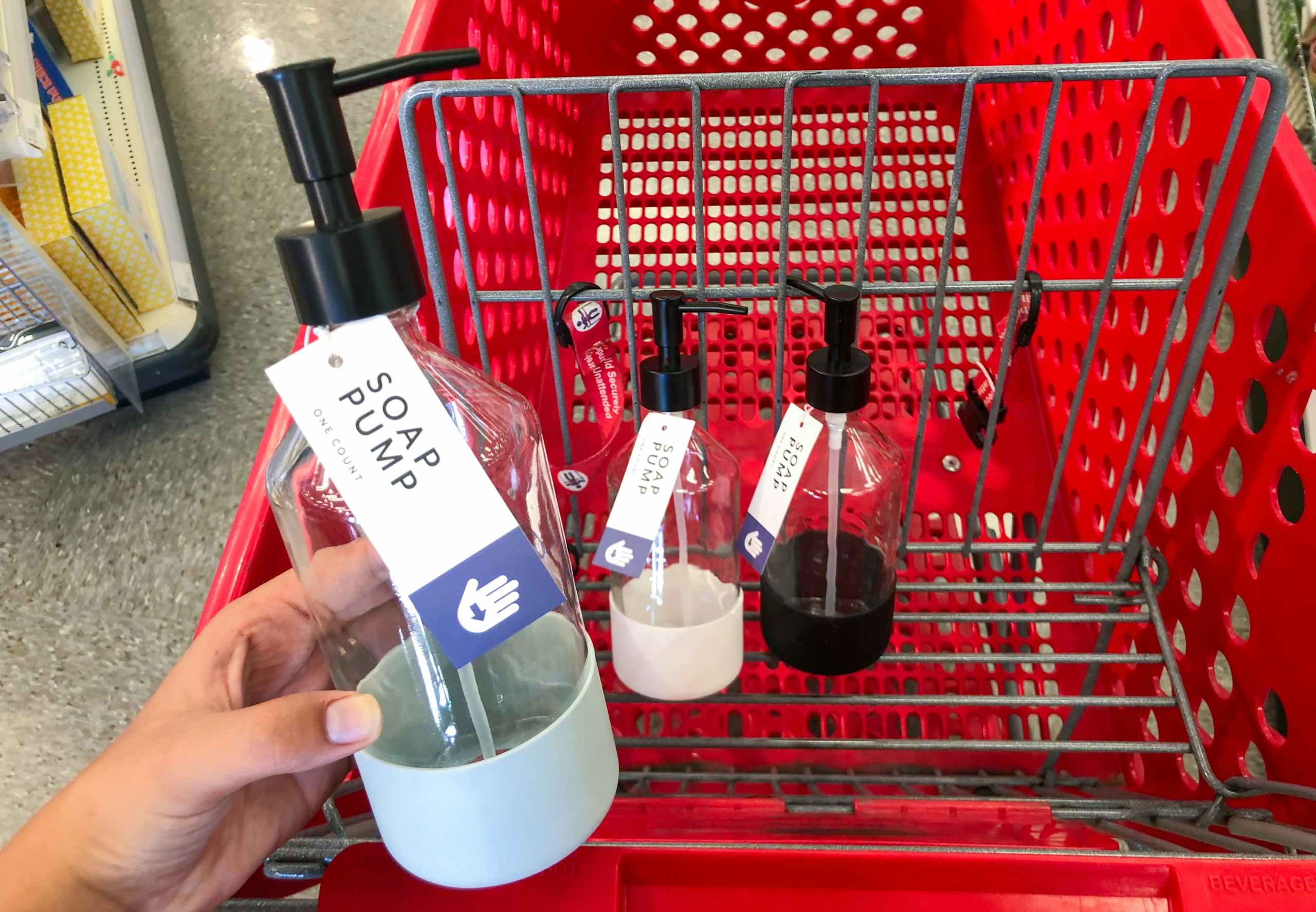 hand holding soap pump in front of shopping cart with other soap bottles in it