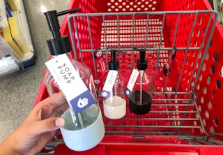 hand holding soap pump in front of shopping cart with other soap bottles in it