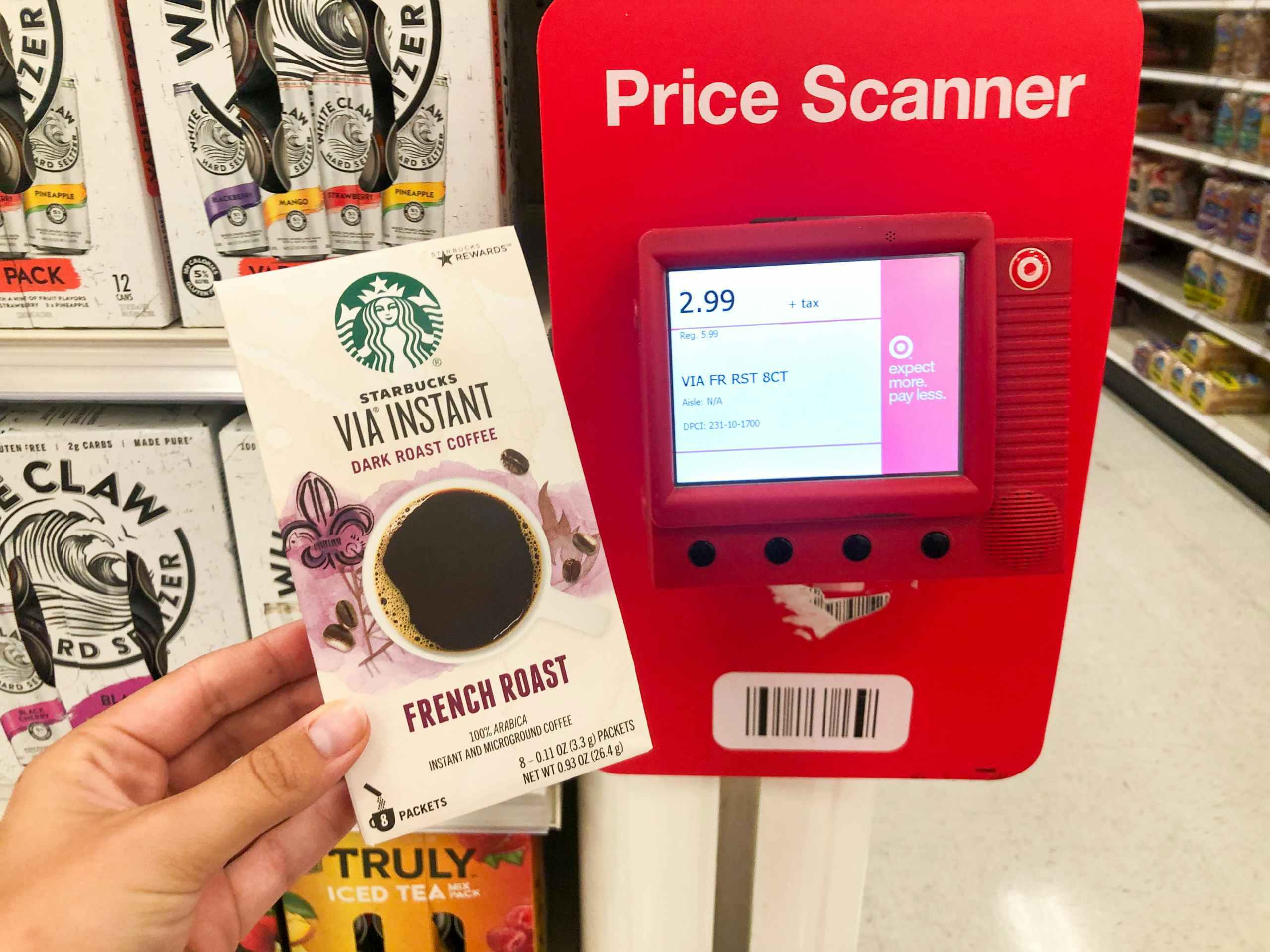 Hand holding Starbucks instant coffee packets in front of price checker