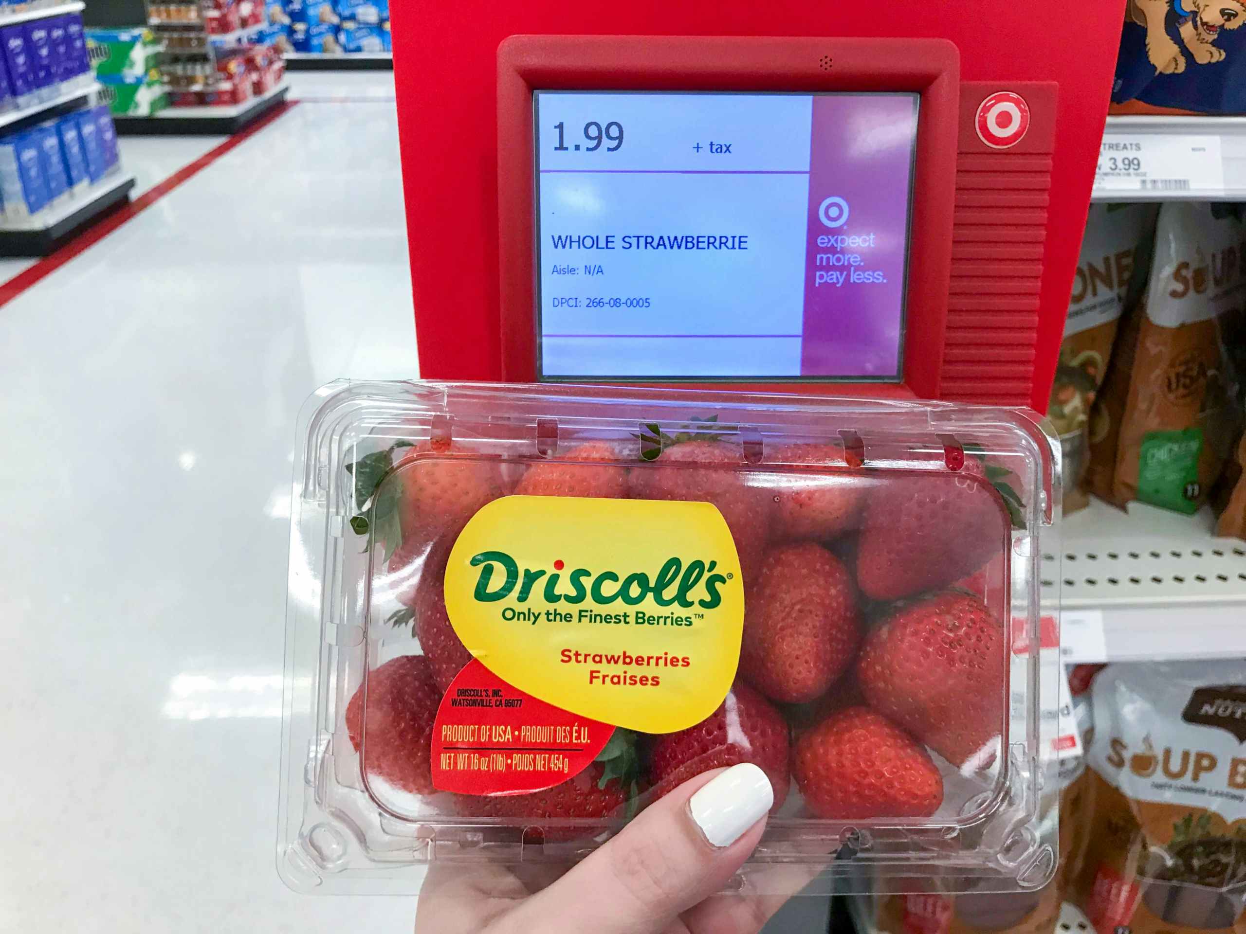 hand holding 1-pound package of fresh strawberries in front of price scanner at Target