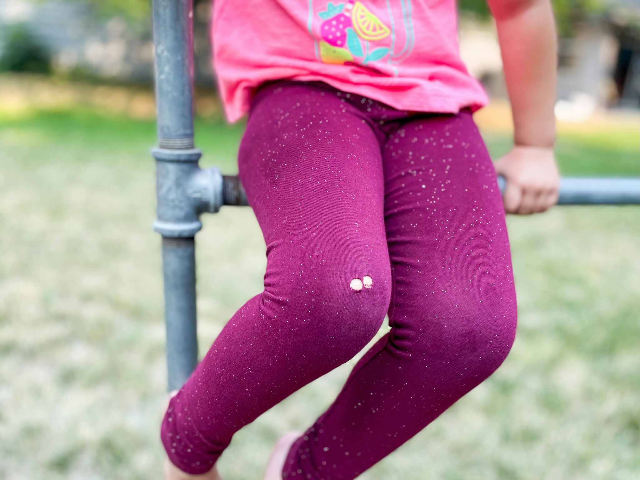 a kid sitting down with ripped leggings on