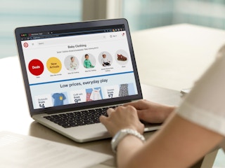 A person using a laptop, looking at the Baby Clothing section on Target's website.
