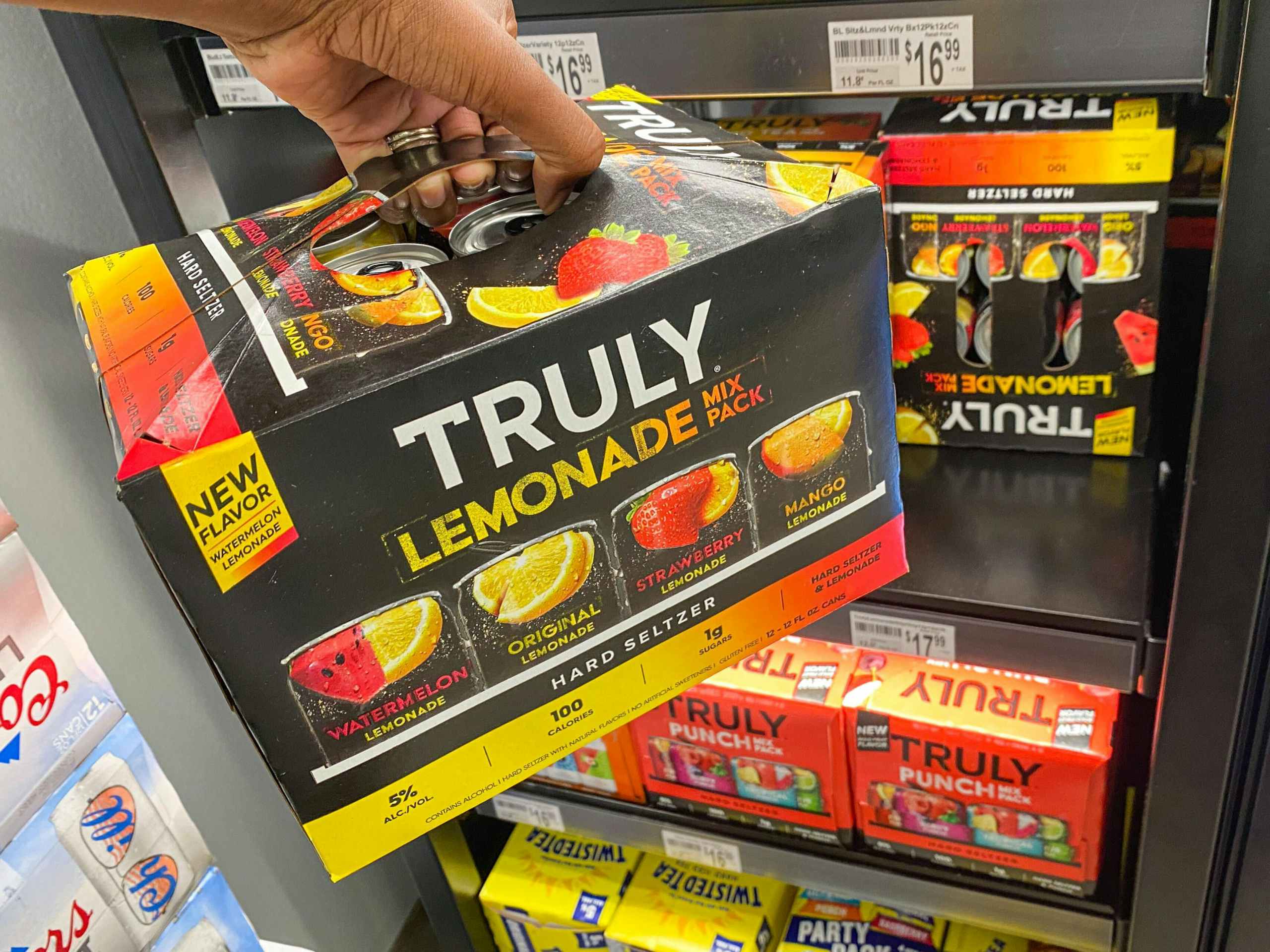 hand grabbing Truly lemonade off of gas station cooler shelf