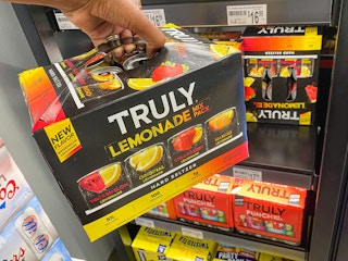 hand grabbing Truly lemonade off of gas station cooler shelf