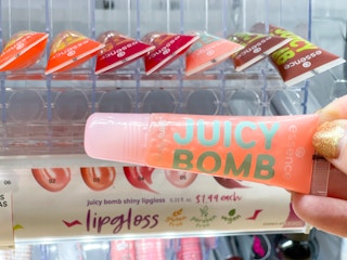 hand holding essence lip gloss in front of display