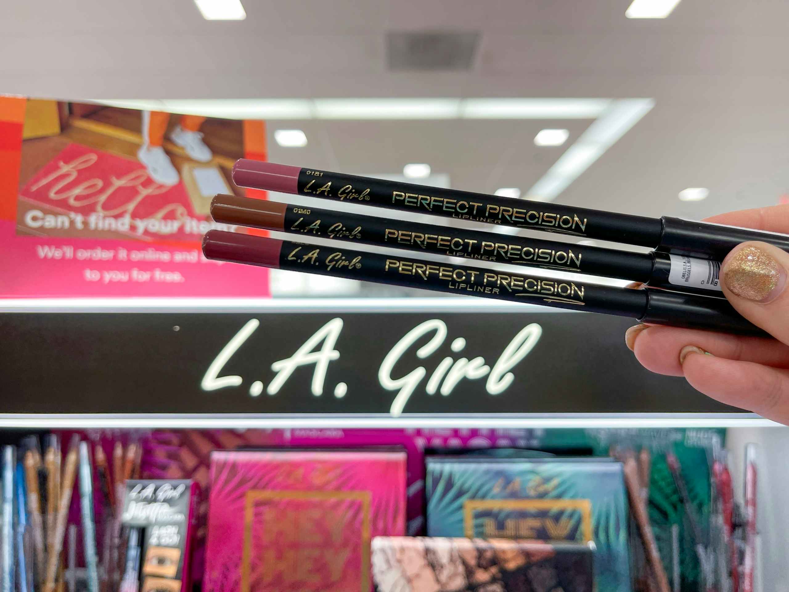 hand holding L.A. Girl lip liners in front of display