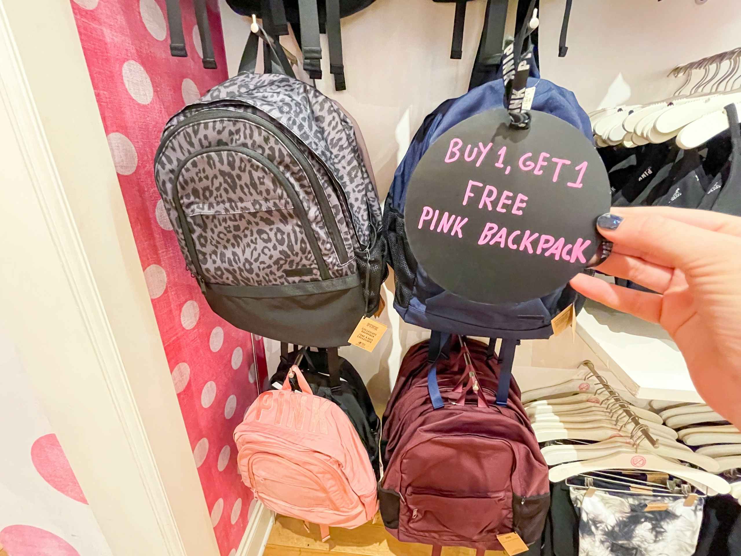 Victoria's Secret backpacks hanging with hand holding sale sign