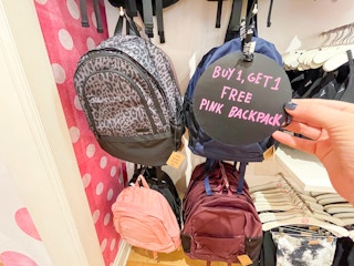 Victoria's Secret backpacks hanging with hand holding sale sign
