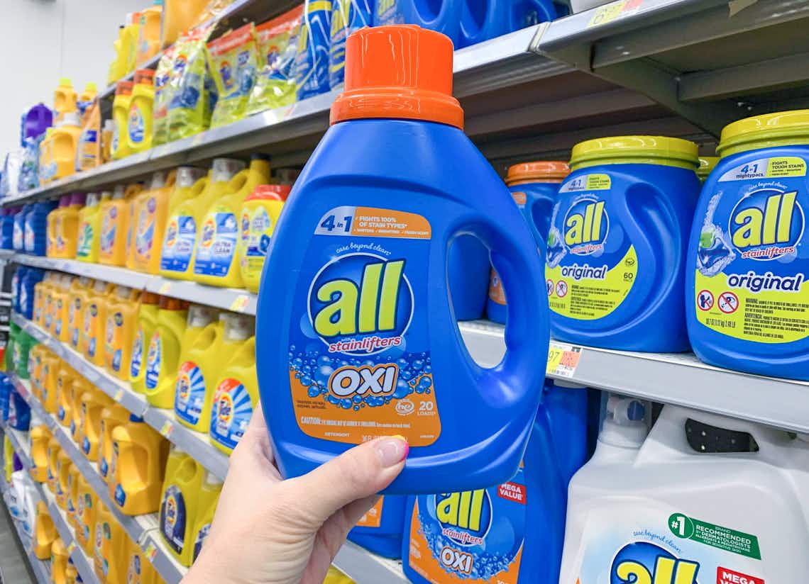 bottle of all oxi liquid laundry detergent held up in front of other laundry detergents in walmart store aisle