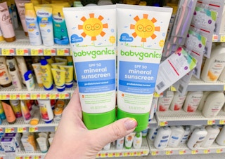 two bottles of babyganics sunscreen held in front of all sunscreens at walmart