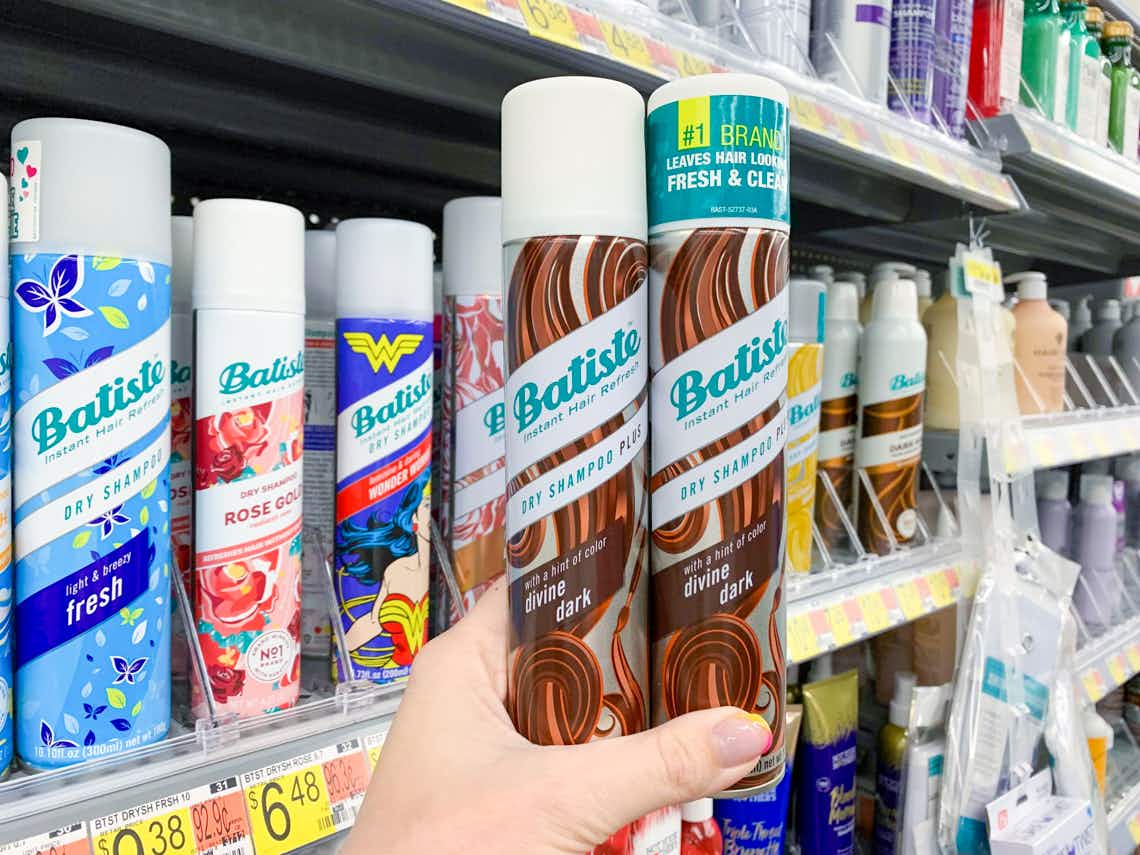 two cans of divine dark batiste dry shampoo held in front of other batiste dry shampoos