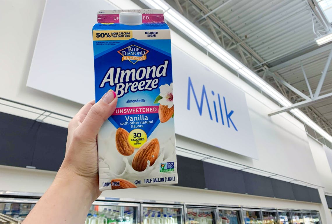 carton of blue diamond almond breeze almondmilk held up in front of milk sign at walmart
