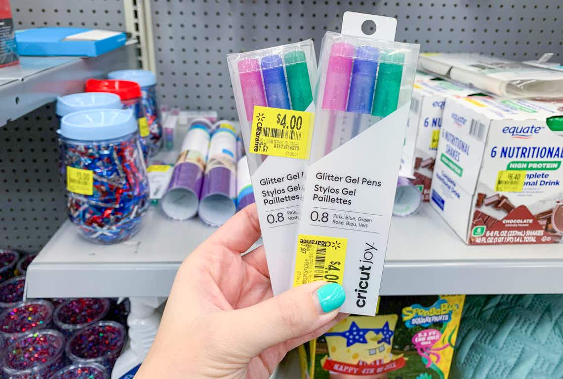 two packages of cricut joy gel pens held up in front of clearance stuff at walmart