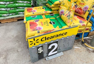 miracle gro potting soil stacked on the ground with walmart clearance sign in front