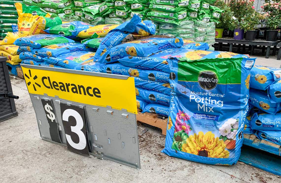 miracle gro moisture control potting soil stacked on ground with walmart clearance sign in front
