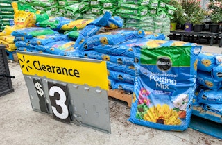 miracle gro moisture control potting soil stacked on ground with walmart clearance sign in front