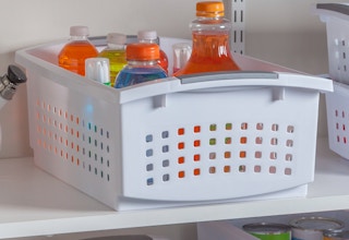 stock photo of sterilite stacking storage basket staged on shelf with bottles in it