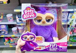 zuru pets alive fifi the flossing sloth robot toy held in front of other toys