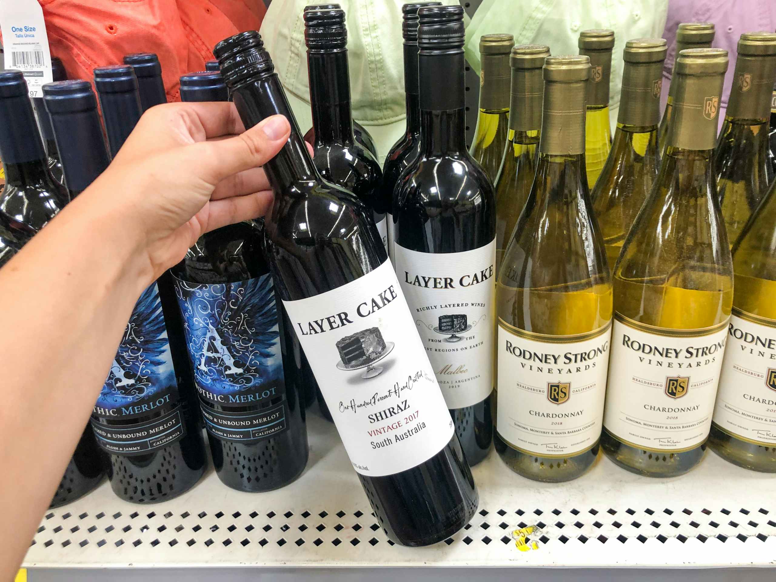 hand holding bottle of wine in front of clearance display at Walmart