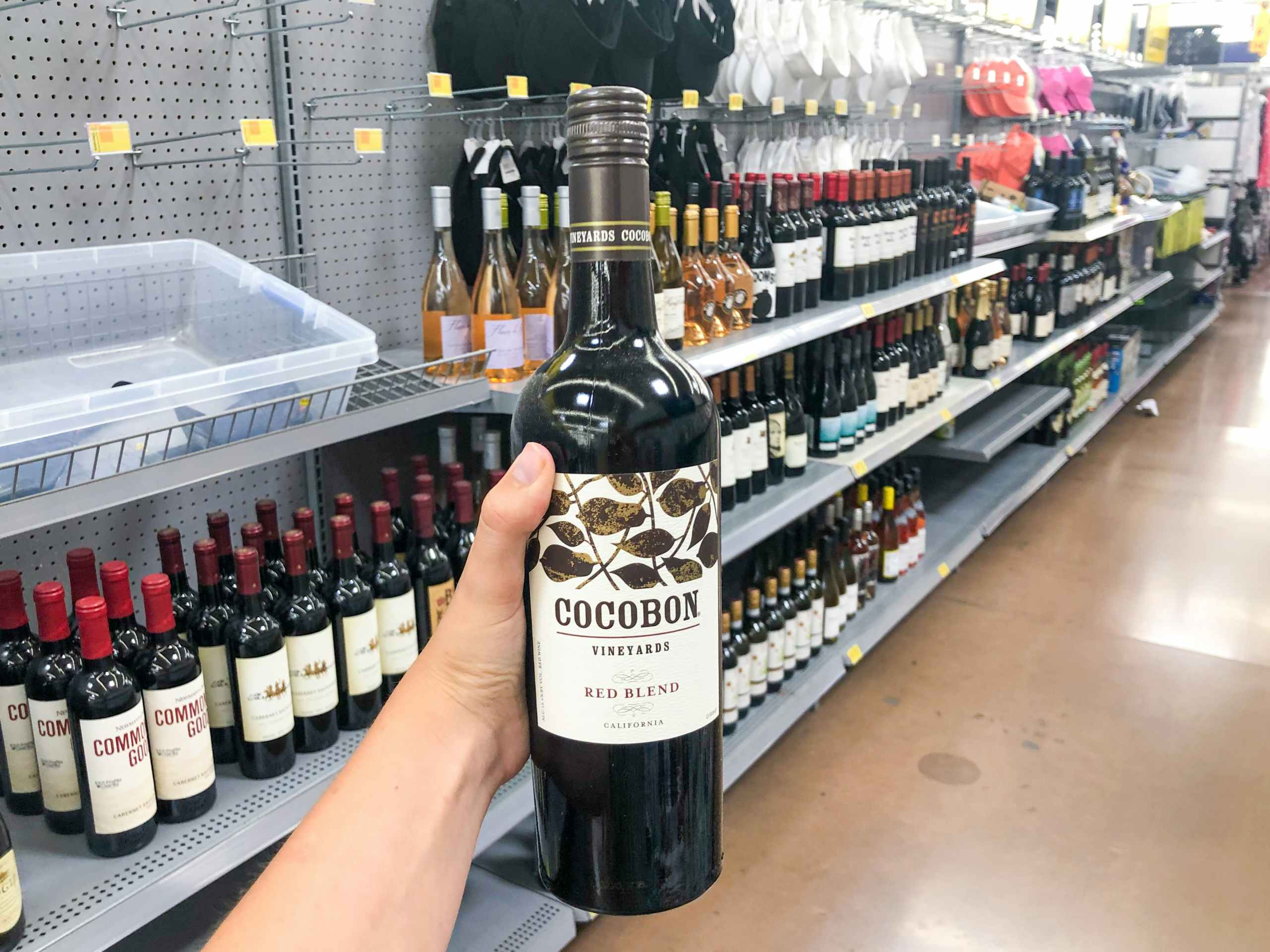 hand holding bottle of wine in front of clearance display at Walmart