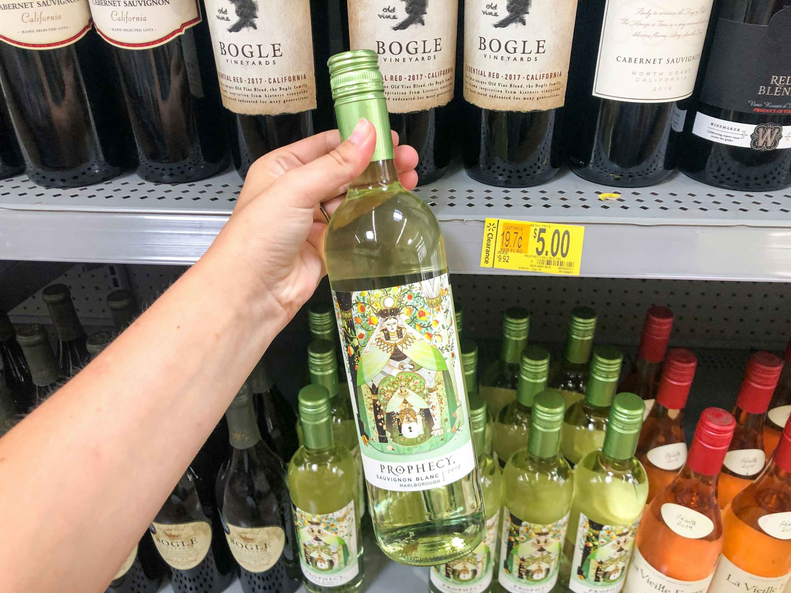 hand holding bottle of wine in front of clearance display at Walmart