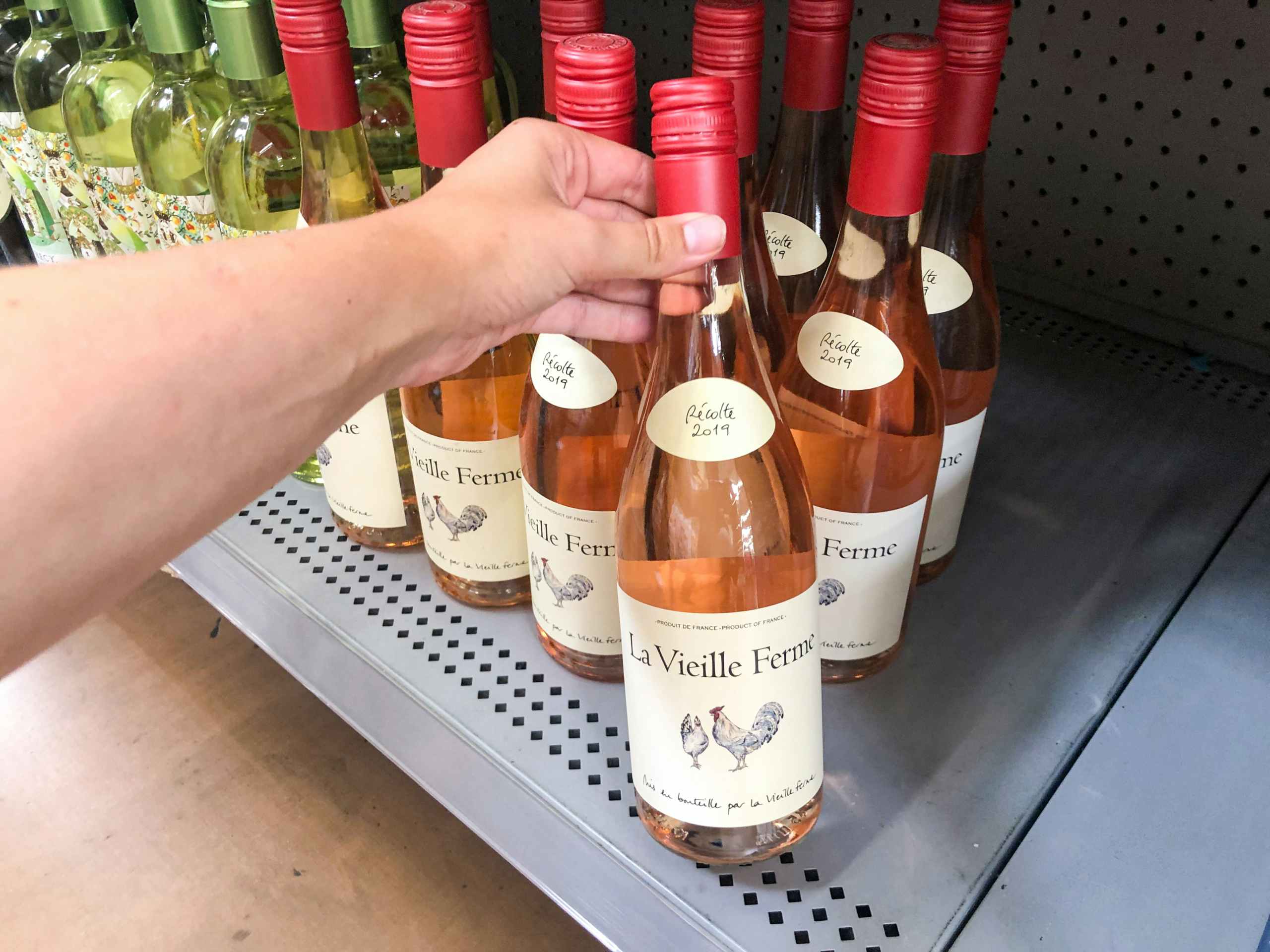 hand holding bottle of wine in front of clearance display at Walmart