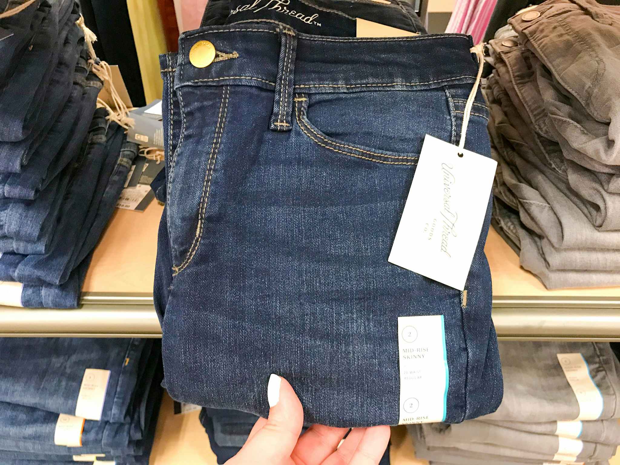 hand grabbing a pair of universal thread women's jeans at target