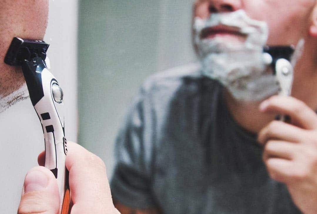 A man shaving his face with shaving cream and a BIC Hybrid Flex 5 razor.