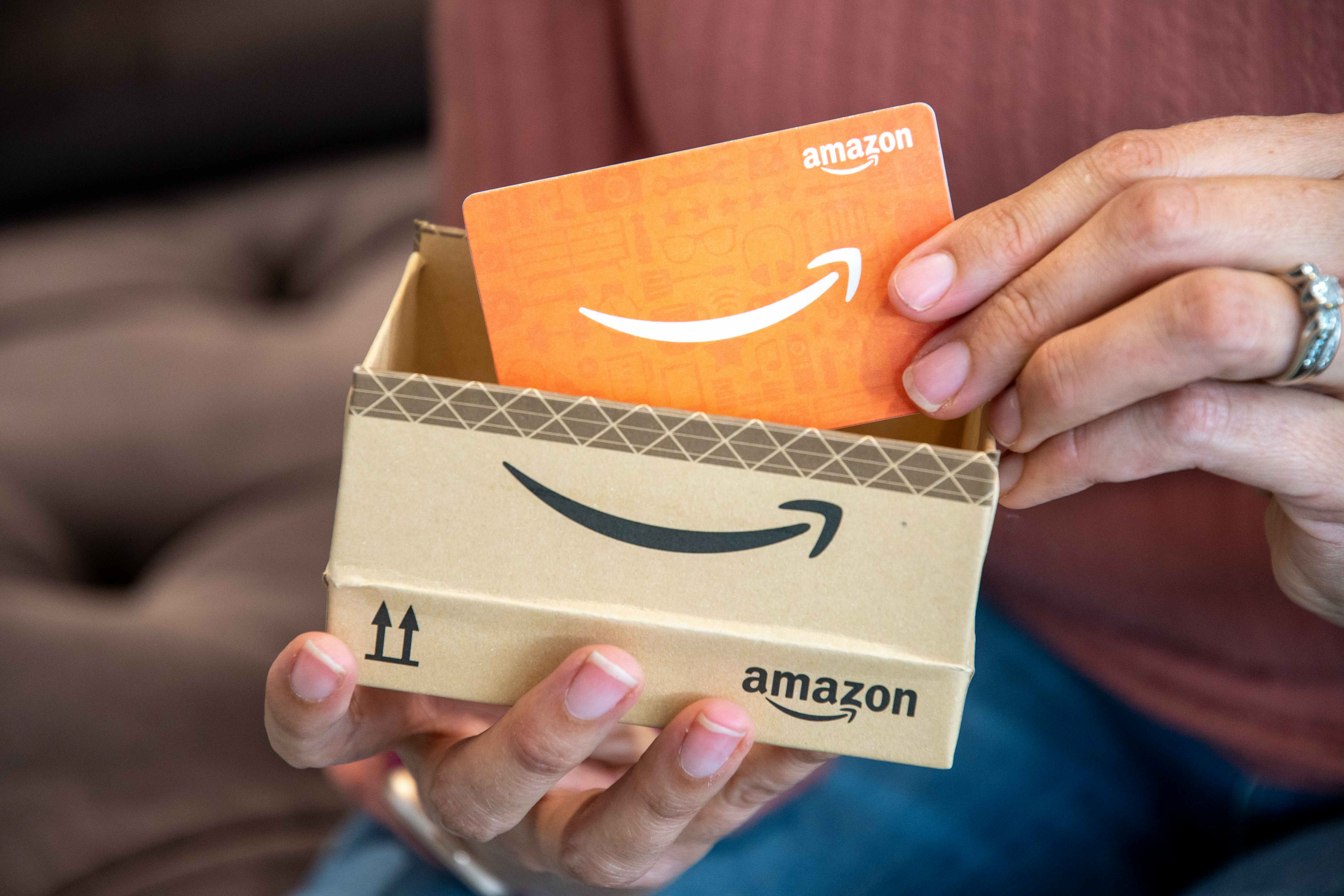 person removing amazon gift card from box