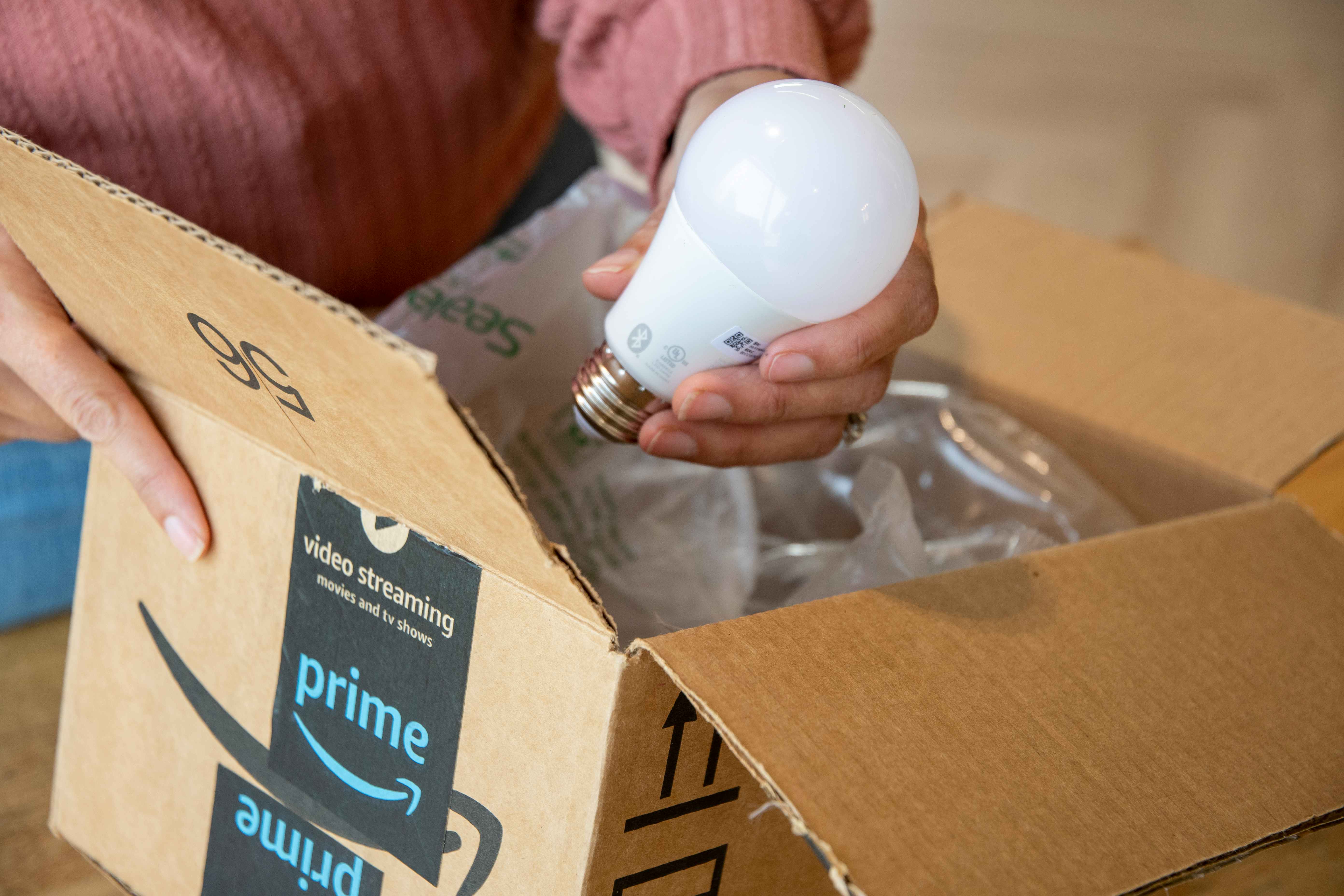 a person pulling out a smart bulb out of an amazon box