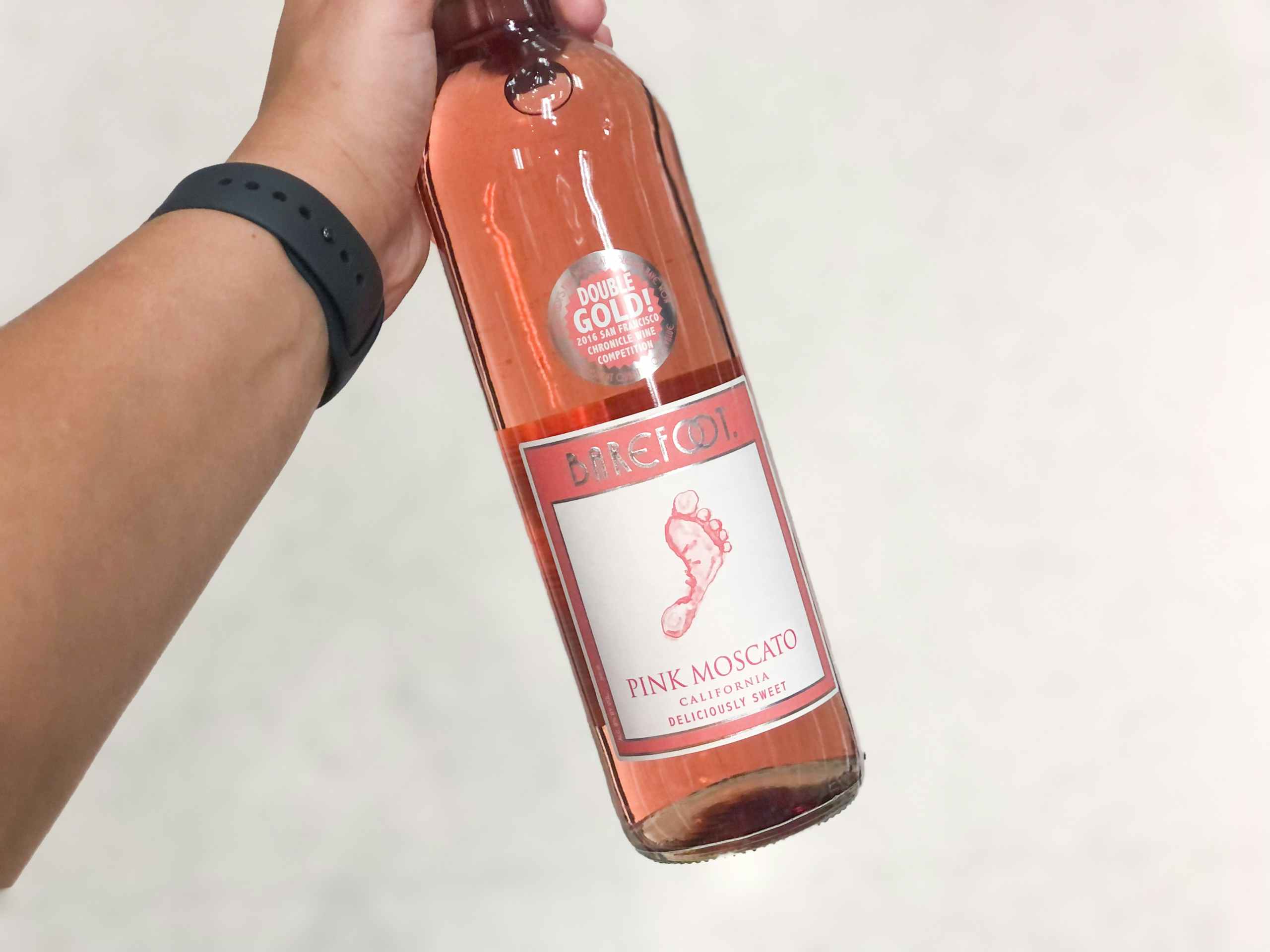 hand holding bottle of Barefoot wine in store aisle