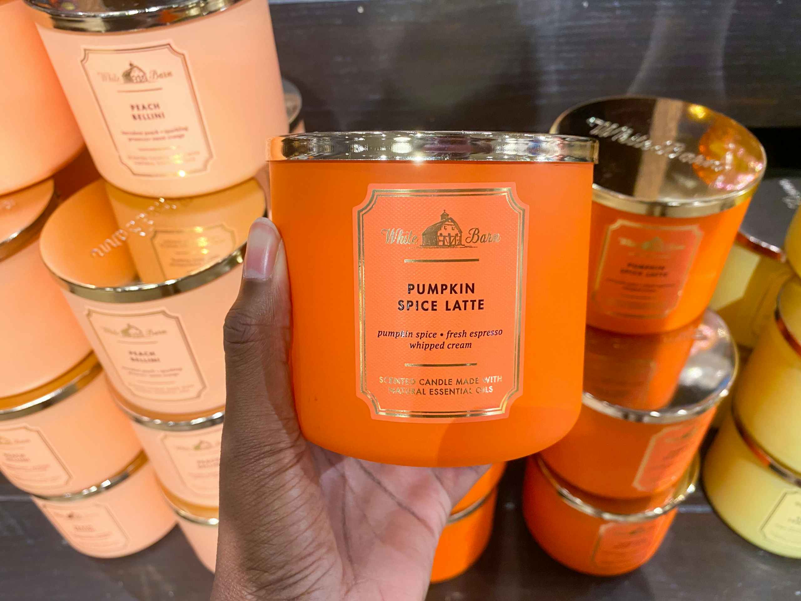 someone holding a fall scented candle in front of other fall scented candles
