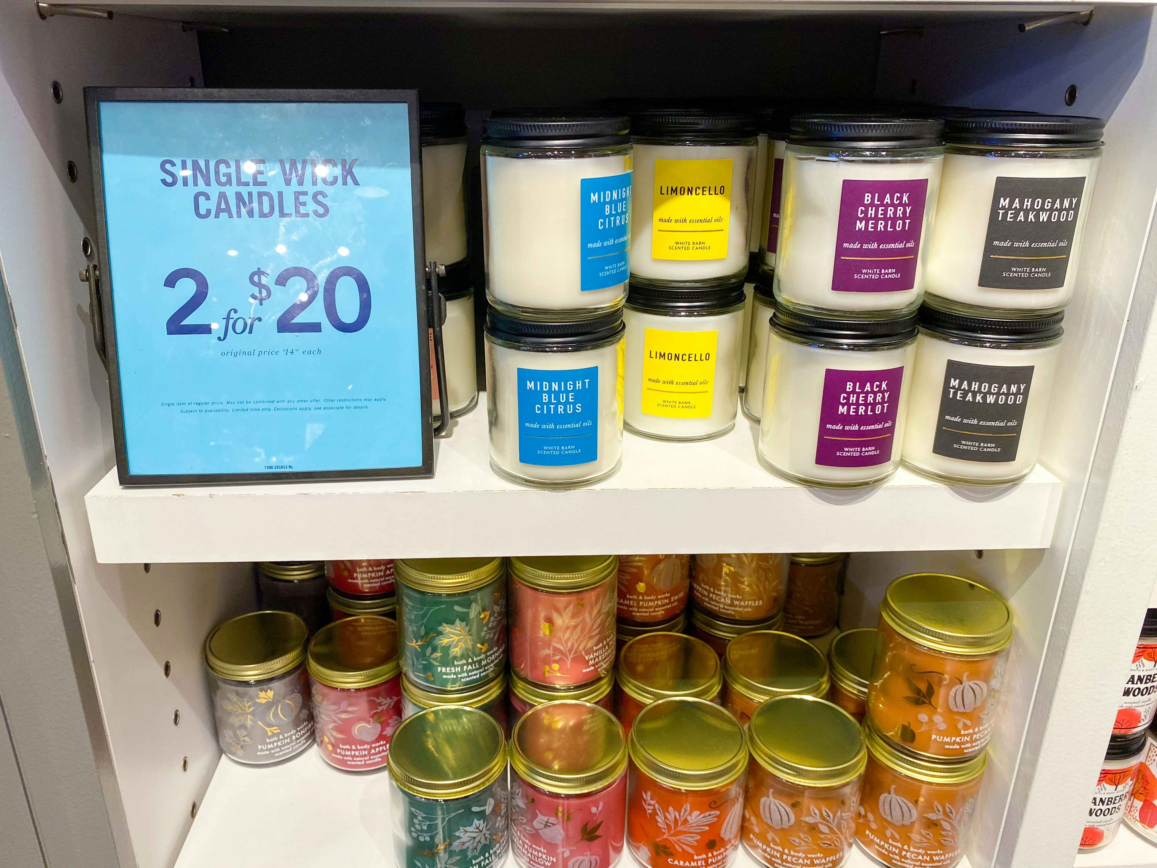 A display of single wick candles with a two for twenty dollars sale sign inside Bath & Body Works.