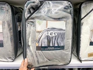 someone taking an ugg blanket off the shelf in bed bath and beyond