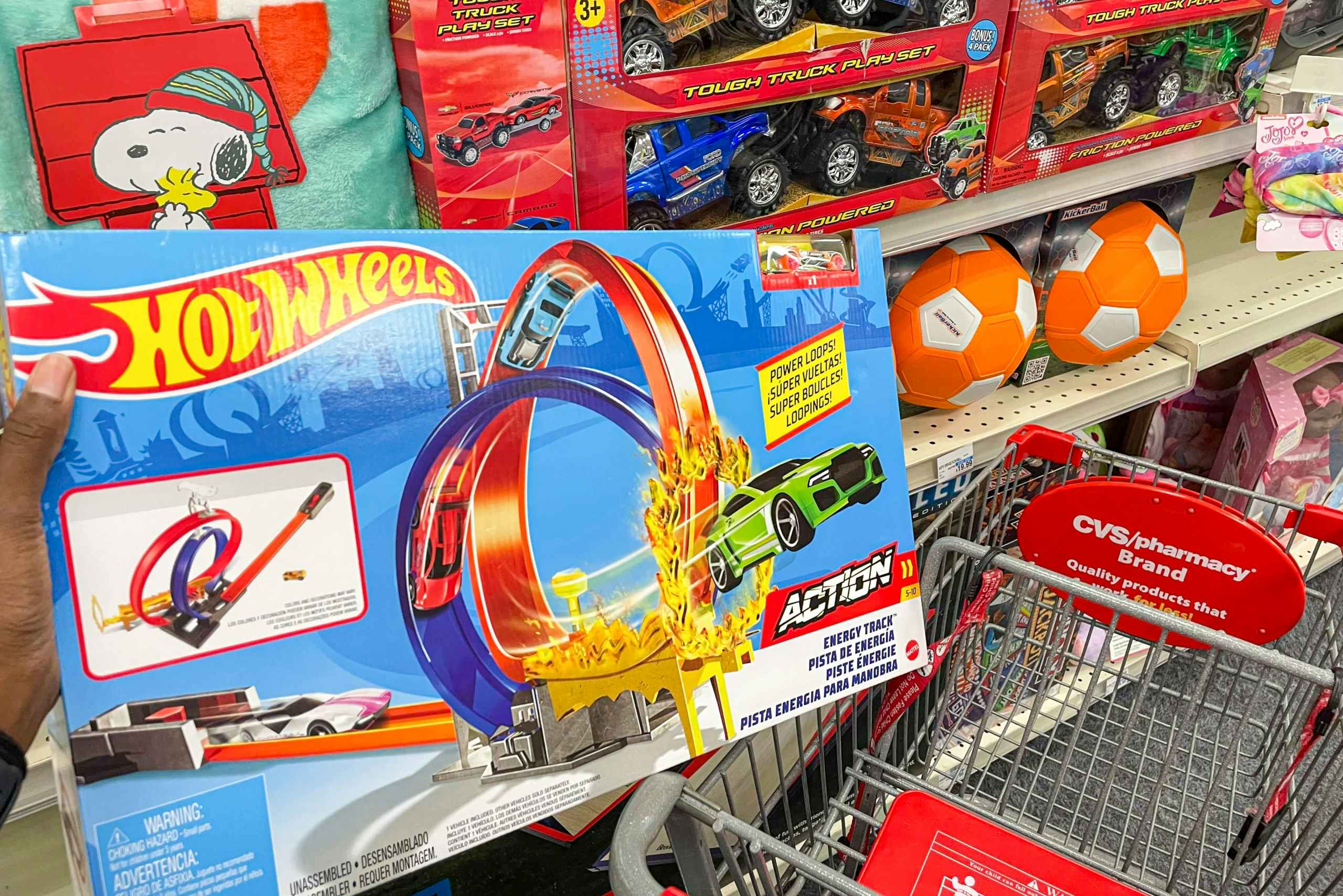 A person putting a Hot Wheels toy into a CVS shopping cart during a Black Friday event.