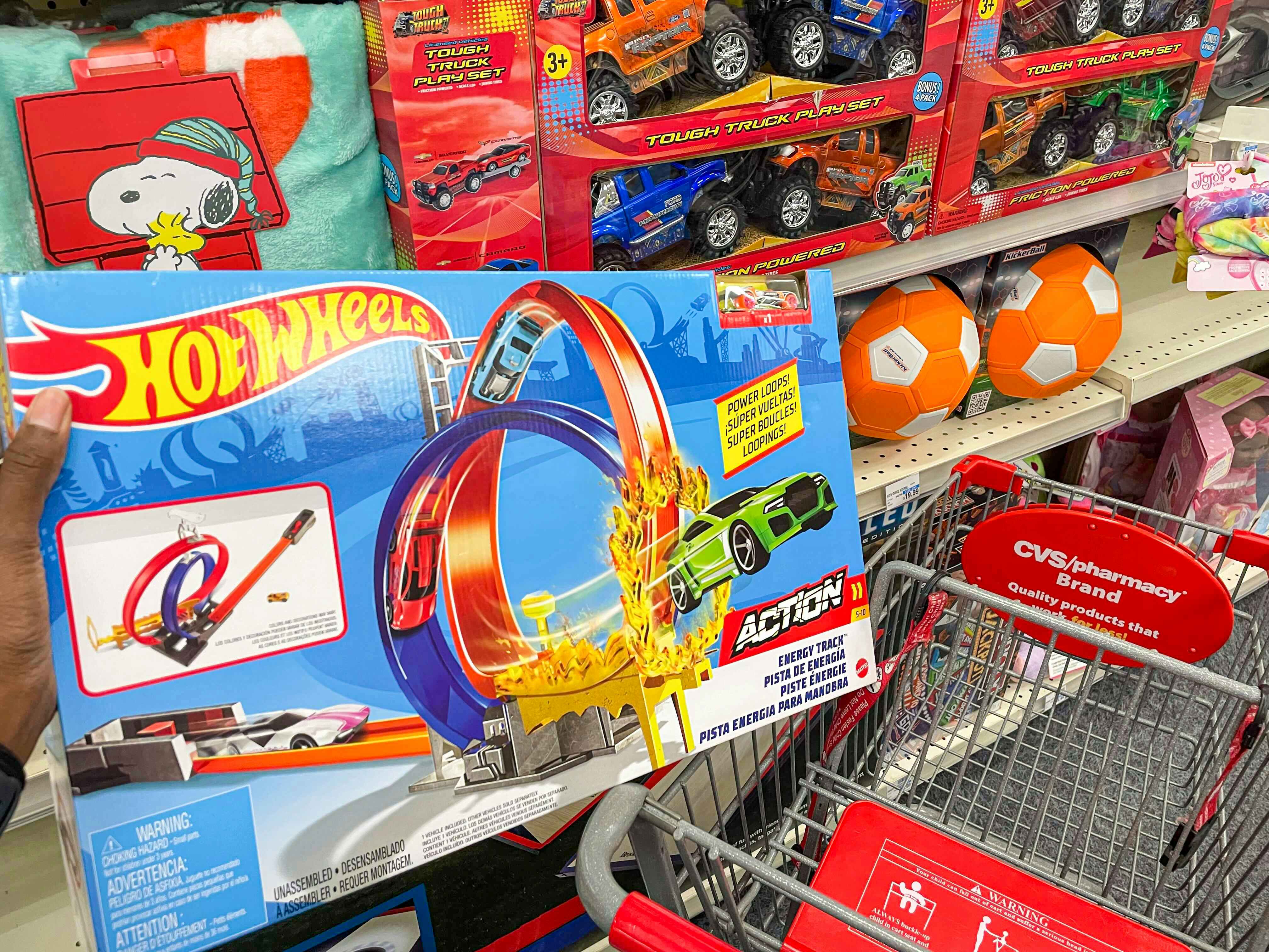 A person putting a Hot Wheels toy into a CVS shopping cart during a Black Friday event.