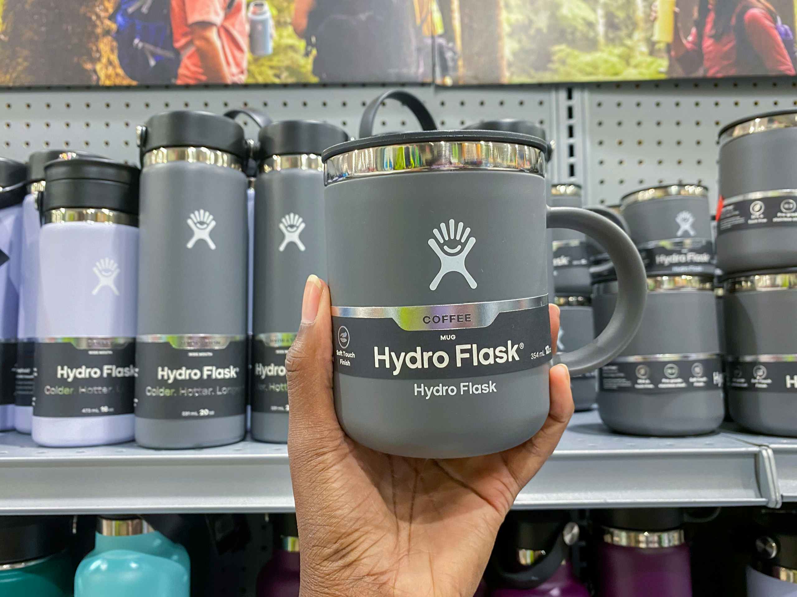 a hydroflask being held in front of a display of other hydrflasks